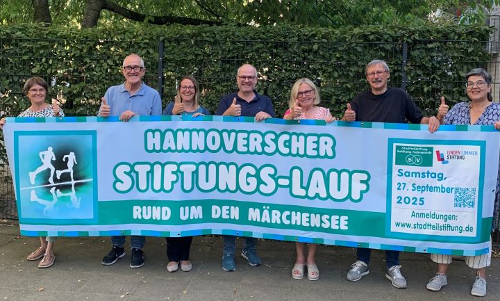 Frauen und Männer halten das Banner für den diesjährigen Stiftungslauf hoch 